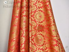 an orange and gold brocaded curtain hanging on a white wall