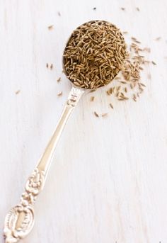 a spoon filled with seeds on top of a wooden table