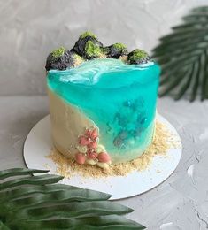 there is a cake with blue and green frosting on the table next to leaves