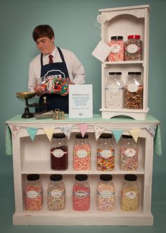 a man standing behind a counter filled with lots of candy