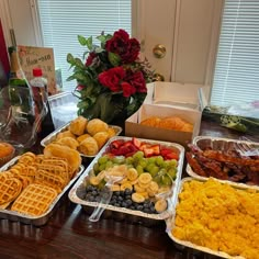 a table filled with lots of different types of breakfast foods and flowers in vases