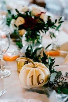 the table is set with white pumpkins and greenery for an elegant fall wedding