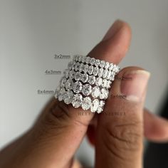 a woman's hand holding three rows of diamond rings in her left hand, with the size shown below