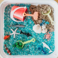 a plastic container filled with sand and toys