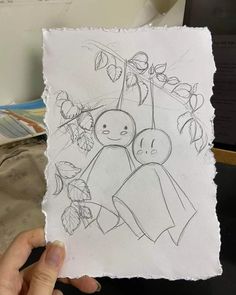 someone holding up a drawing of two people in front of a tree with leaves on it