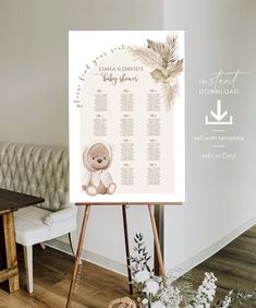 a baby shower sign sitting on top of a wooden easel next to a couch