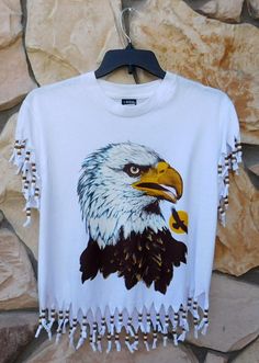 an eagle on a white t - shirt with tassels hanging from it's chest