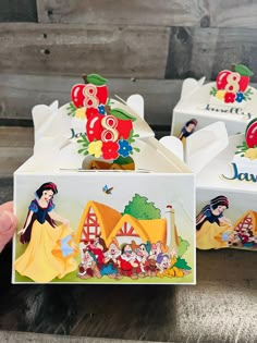 someone is holding up some boxes with snow white and the seven dwarfs designs on them