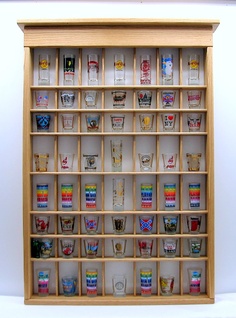 a wooden shelf filled with glasses on top of a white floor next to a wall