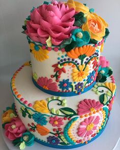 a three layer cake decorated with colorful flowers