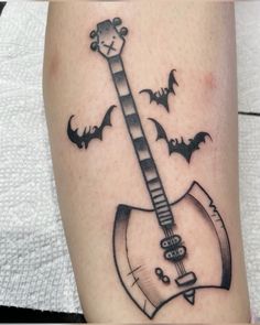 a black and white photo of a guitar with bats on it's side tattoo