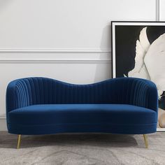 a blue couch sitting in front of a painting on the wall next to a white swan