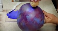 someone is painting an egg with blue and purple paint