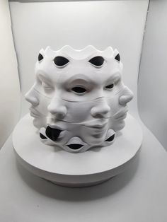 a white sculpture with black dots on it