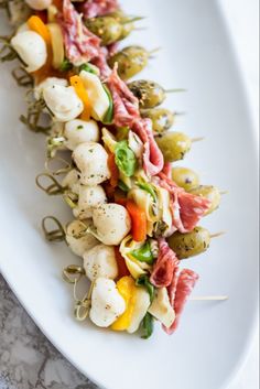 an appetizer is served on a white plate with toothpicks and vegetables