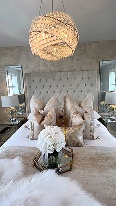 a bedroom with a chandelier hanging from the ceiling and pillows on the bed