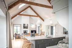 an open kitchen and living room area with white walls, wood beams and wooden flooring