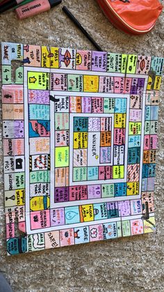 a colorful board game sitting on top of a carpet next to markers and pencils