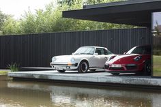 two porsches are parked next to each other in front of a house on the water