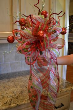 a woman is holding a christmas decoration in her hand while standing next to the kitchen counter