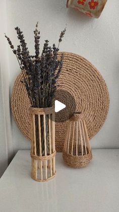 two vases with lavender flowers in them on a white table next to a basket