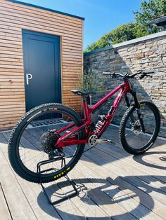 a red bike parked on top of a wooden deck next to a building with a door