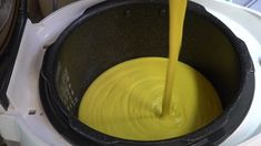 a yellow liquid being poured into a black pot