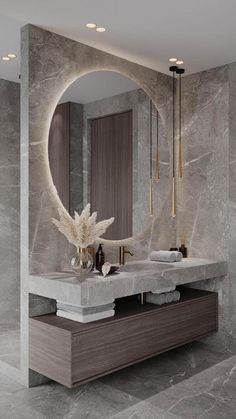 a bathroom with marble walls and flooring has a large circular mirror above the sink