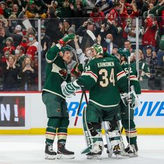 the hockey players are congratulating each other on the ice as fans cheer in the background