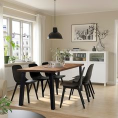 a dining room table with black chairs in front of a window