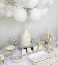 a table topped with lots of desserts and white balloons