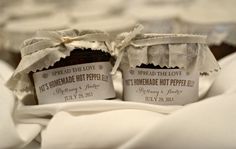 two jars of spread the love homemade hot pepper jelly sitting on top of a white cloth