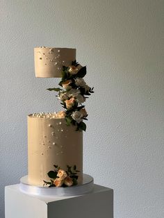 a three tiered cake with white flowers on top and a beige lamp hanging from the side