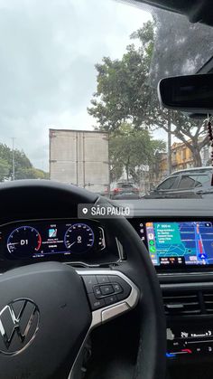 the dashboard of a car is shown in front of other cars and trees on a cloudy day