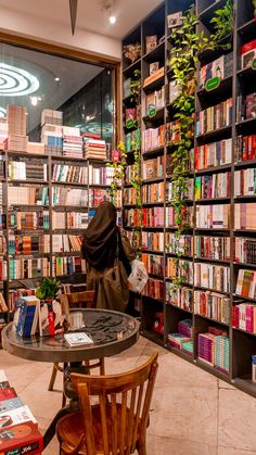 a room filled with lots of books on shelves next to a table and two chairs