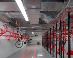 an indoor bike storage area with red and black bicycle racks on the wall next to it