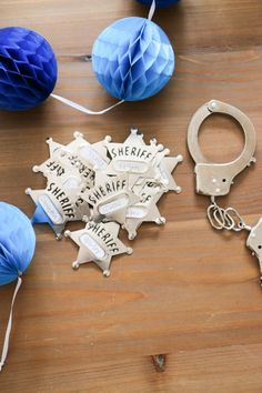 some blue and white paper decorations on a wooden table with handcuffs, balls and paper lanterns