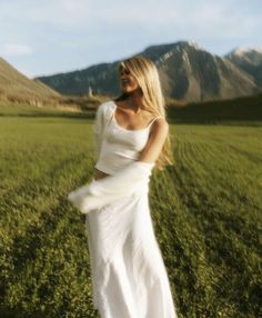 a woman in a white dress standing in a field