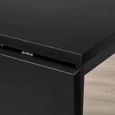 a close up of a black table with a drawer on the bottom and an electronic device attached to it