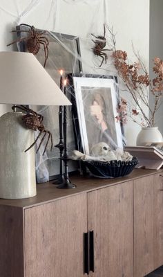 a wooden cabinet with candles and pictures on it, next to a lamp that is turned on