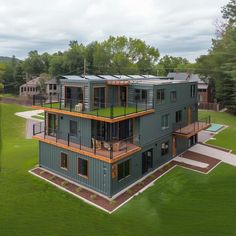 an aerial view of a two story house in the middle of a green field with trees