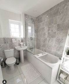 a white bathroom with grey tile walls and floor