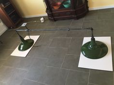 two green lamps sitting on top of a tile floor next to a white piece of paper