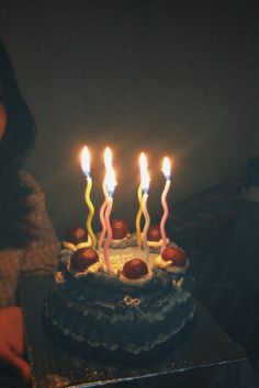 a woman sitting in front of a cake with lit candles