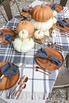 the table is set with pumpkins, plates and silverware