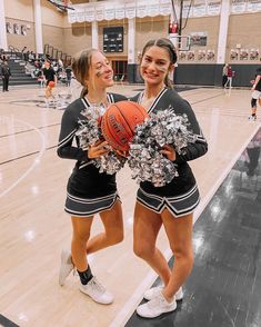 two girls in cheerleader outfits holding a basketball