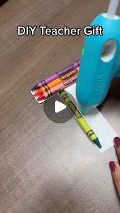 a person is holding some crayons and scissors on a table with the words diy teacher gift in front of them