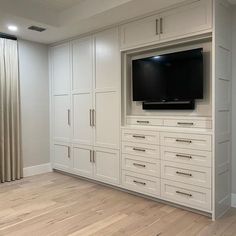 an empty room with white cabinets and a flat screen tv mounted on the side of it