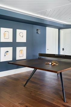 a ping pong table in an empty room with blue walls and wood flooring