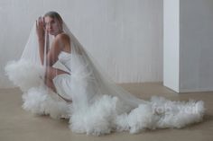 a woman in a white wedding dress sitting on the floor